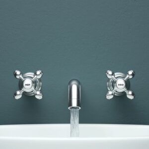 an open faucet attached to a blue wall